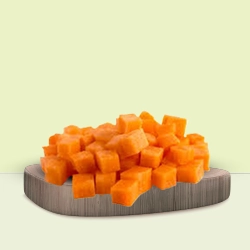 Diced orange carrots in uniform cubes are displayed on a wooden cutting board.